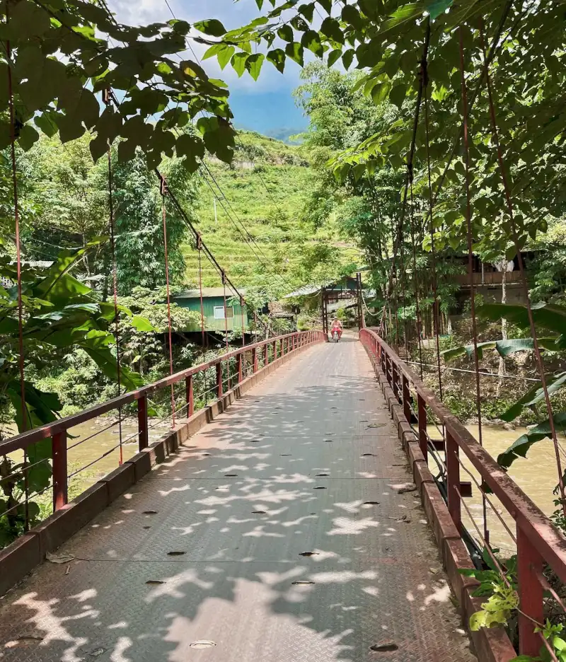 alte, rote Bruecke aus Metall fuert ueber einen Fluss