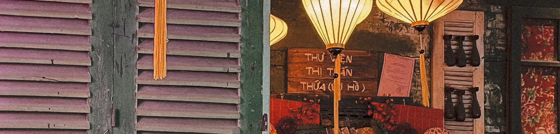 Lampions Orange vor einem Hauseingang mit Fensterlamellen aus Holz