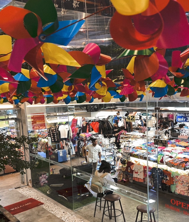 ho chi minh city – geschichte und must-sees. blick in den berühmten ben thanh markt mit bunten waren wie t-shirts und kleider.