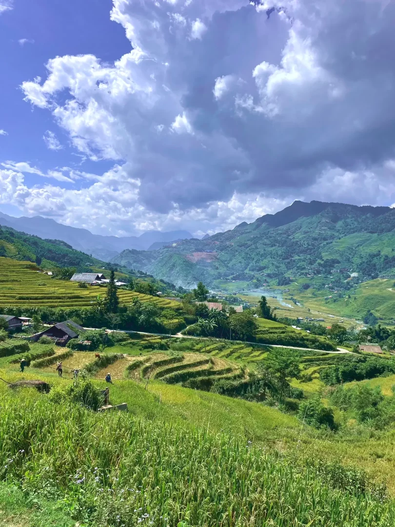 blick ins tal mit einer vielzahl von grünen reisterrassen. einige holzhäuser verteilen sich im tal und im hintergrund eine vielzahl von bergketten