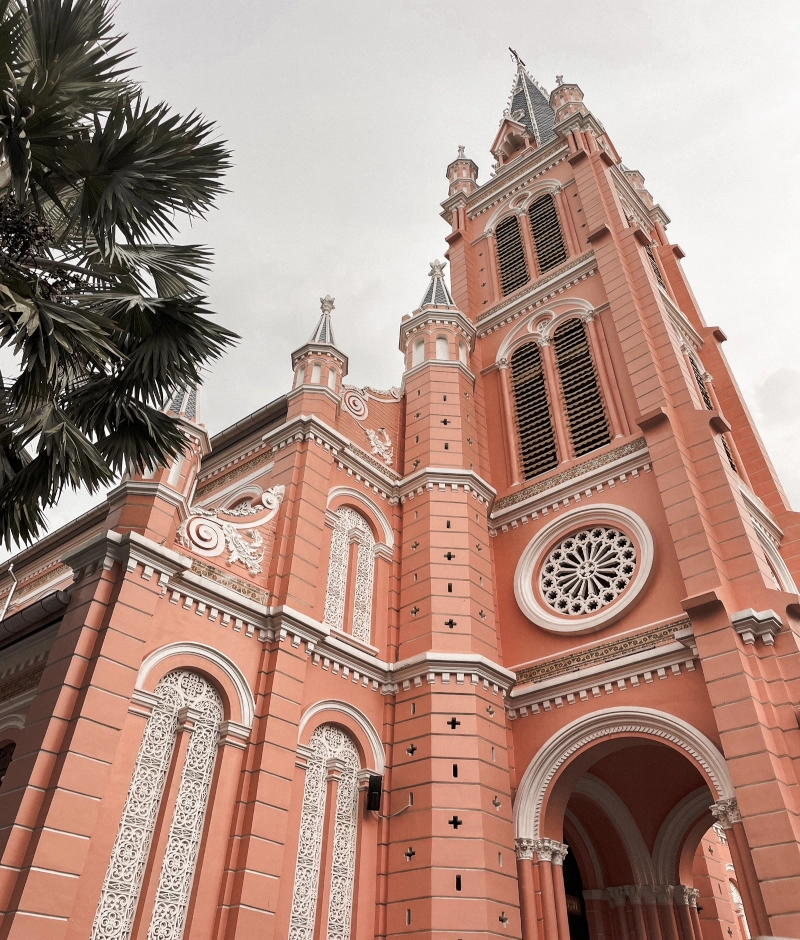 ho chi minh city – geschichte und must-sees. auffällig farbenfrohe tan dinh kirche in der Farbe rosa. fotografiert aus der frosch perspektive. schöner spitzer kirchturm in weiß ragt empor