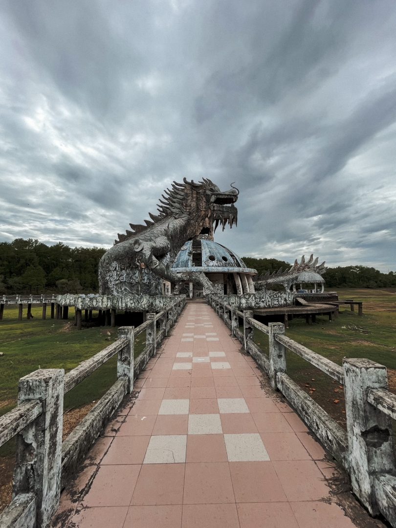 ein langer mit roten steinen gepflasterter weg. am ende steht ein großerr drachen aus stein. in zentral vietnam im waterpark gelegen.